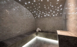 Luxurious spa interior featuring a steam room with a starry ceiling, elegant stone walls, and ambient lighting, designed for relaxation and wellness.