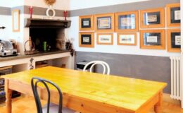 Cozy dining area featuring a wooden table surrounded by black and white chairs, with a decorative fireplace and framed artwork on the walls. The room has a warm and inviting atmosphere, ideal for gatherings.