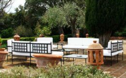 Outdoor seating area with modern black and white furniture surrounded by greenery and decorative terracotta lanterns, ideal for relaxation and social gatherings.