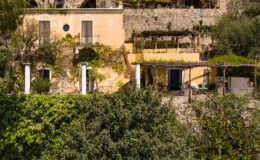 Charming hillside villa surrounded by lush greenery, featuring outdoor terraces and rustic stone architecture, ideal for a serene getaway.