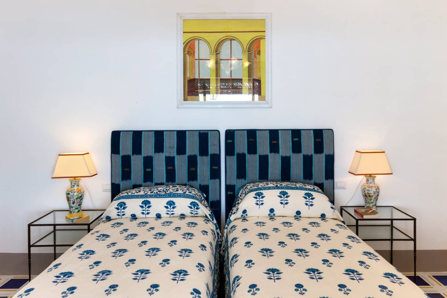 Cozy bedroom featuring two twin beds with patterned bedding, stylish bedside lamps, and a decorative mirror above. Bright and inviting atmosphere with a touch of elegance. | Only on SopranoVillas