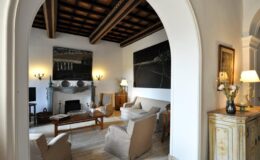 Spacious living room with vaulted wooden ceiling, elegant furniture, and contemporary artwork, featuring a cozy fireplace and soft lighting to create a welcoming atmosphere.