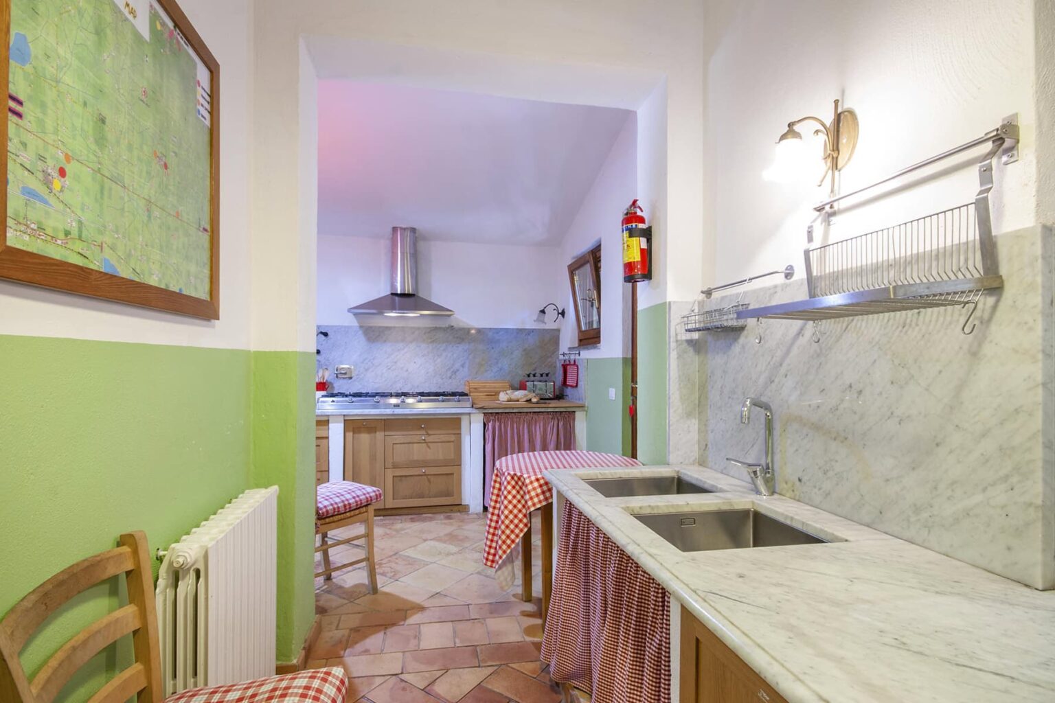 Bright and spacious kitchen featuring marble countertops, a modern stove, and a cozy dining area with checkered tablecloths, complemented by green and white walls. | Only on SopranoVillas