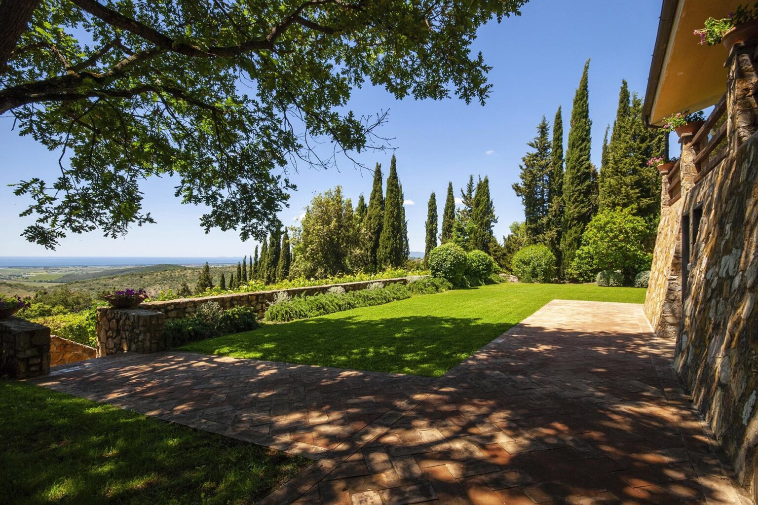 Scenic view of a landscaped garden with lush greenery, tall cypress trees, and a stone pathway, showcasing a tranquil outdoor space ideal for relaxation and nature appreciation. | Only on SopranoVillas