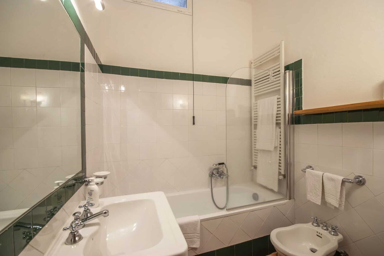 Modern bathroom featuring a bathtub with a shower, sleek sink, and minimalist decor. Bright lighting and clean tiles enhance the spacious feel. | Only on SopranoVillas