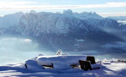 Snow-covered picnic table with a breathtaking view of the mountains in the background, illuminated by soft sunlight. Ideal for winter scenery and outdoor adventure imagery.