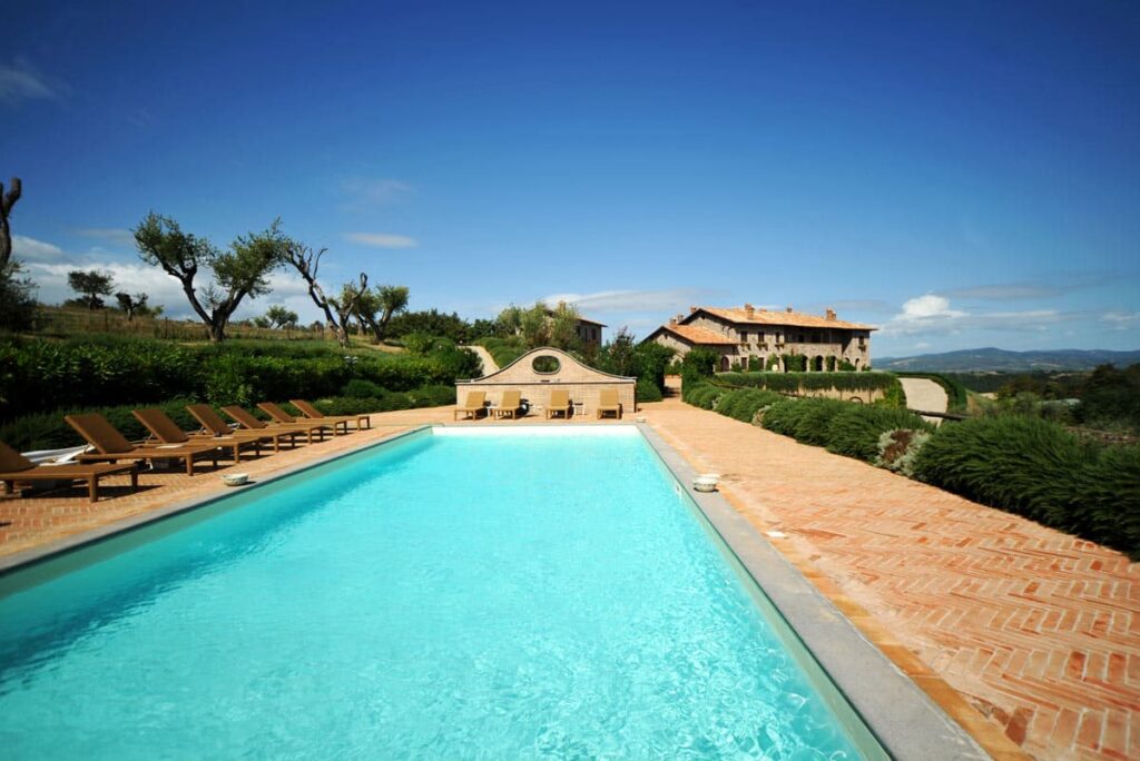 Luxurious villa with a swimming pool surrounded by lush greenery and scenic hills under a clear blue sky. | Only on SopranoVillas