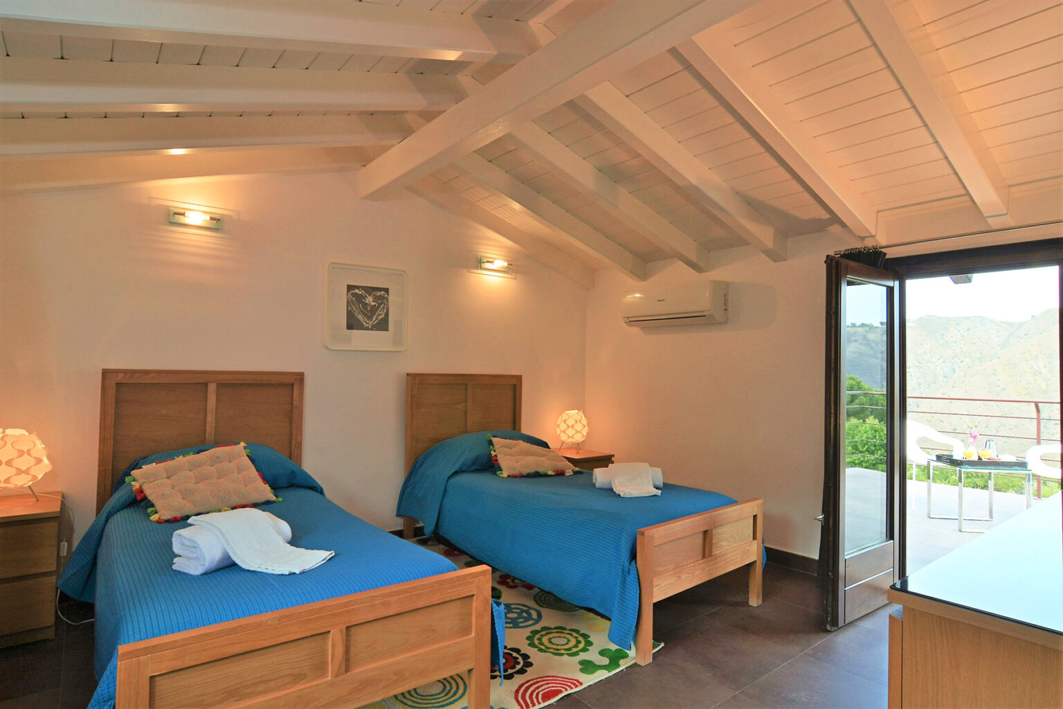 Cozy bedroom featuring two twin beds with blue bedding, wooden furniture, and large windows offering natural light and scenic views. Ideal for a relaxing stay. | Only on SopranoVillas