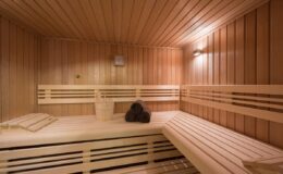 Interior of a wooden sauna featuring benches, soft lighting, and a stack of sauna stones, creating a relaxing atmosphere for wellness and heat therapy.