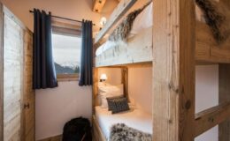 Cozy bunk bed setup in a rustic mountain cabin, featuring wooden frames, plush bedding, and a window with scenic views, ideal for a comfortable stay.