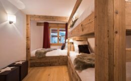 Cozy bedroom featuring wooden bunk beds, warm lighting, and rustic decor, ideal for family or group accommodations in a mountain lodge.