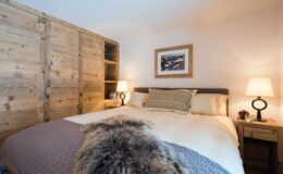 Cozy bedroom featuring a large bed with plush bedding, wooden cabinets, and soft lighting from bedside lamps, creating a warm and inviting atmosphere.