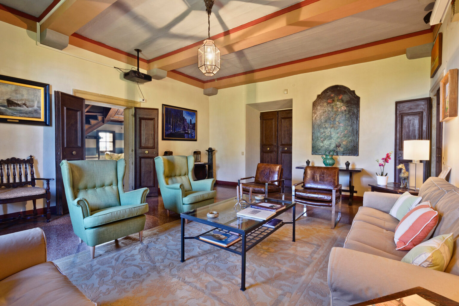 Cozy living room with green armchairs, a beige sofa, and a coffee table, featuring warm lighting and artwork on the walls. The room has a classic design with wooden accents and a welcoming atmosphere. | Only on SopranoVillas