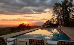 Luxurious outdoor pool area at sunset, featuring comfortable lounge chairs, scenic views of rolling hills, and a tranquil atmosphere, perfect for relaxation and leisure.