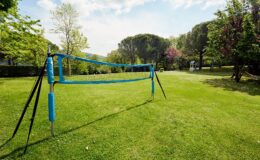 Outdoor volleyball court set up in a grassy park, surrounded by trees and a clear blue sky, ideal for recreational sports and outdoor activities.