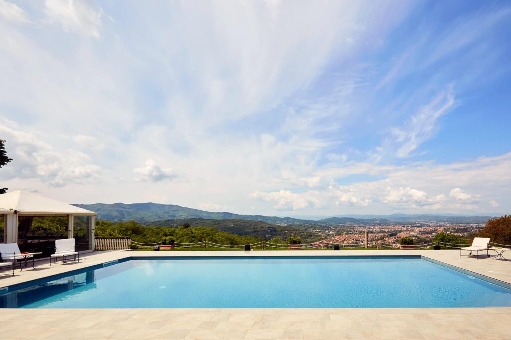 Luxury villa with a stunning infinity pool overlooking a scenic landscape, featuring mountains and a clear blue sky. Ideal for relaxation and outdoor gatherings. | Only on SopranoVillas