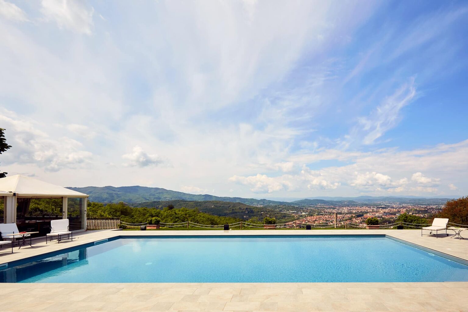 Luxury villa with a stunning infinity pool overlooking a scenic landscape, featuring mountains and a clear blue sky. Ideal for relaxation and outdoor gatherings. | Only on SopranoVillas