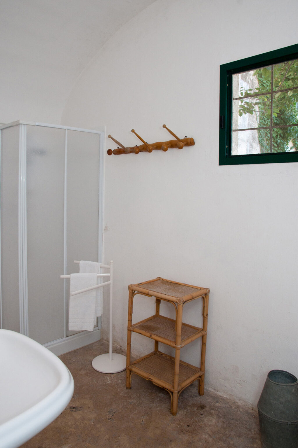 Interior view of a bathroom featuring a glass shower enclosure, a wooden coat rack on the wall, and a bamboo stool, highlighting a minimalist and natural design aesthetic. | Only on SopranoVillas