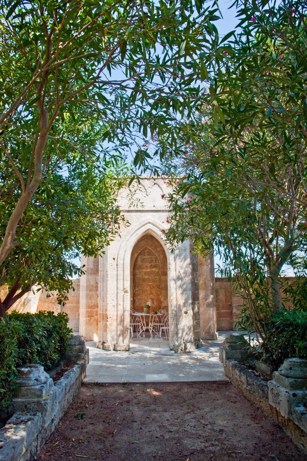 A serene garden scene featuring an ornate stone archway surrounded by lush greenery, creating a tranquil atmosphere. | Only on SopranoVillas