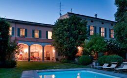 Elegant villa with a swimming pool, illuminated at dusk, surrounded by lush greenery and outdoor seating. Ideal for luxury retreats and vacation rentals.