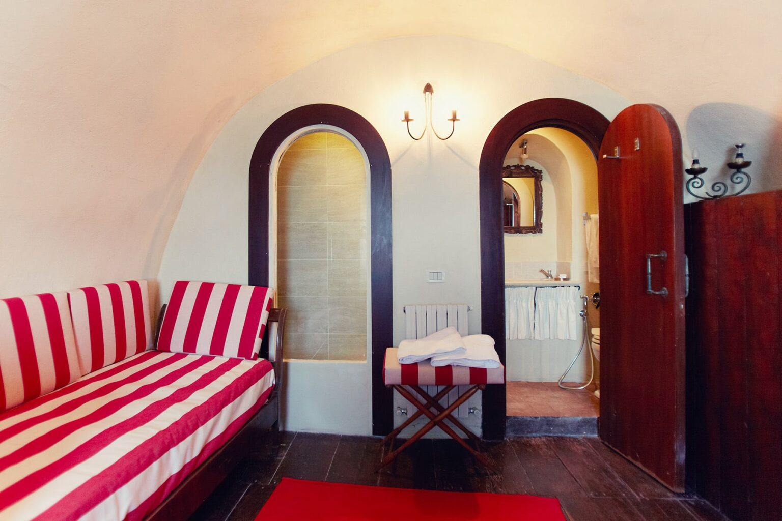 Cozy interior of a uniquely designed room featuring red and white striped seating, arched doorways, and warm lighting, creating a welcoming atmosphere. | Only on SopranoVillas