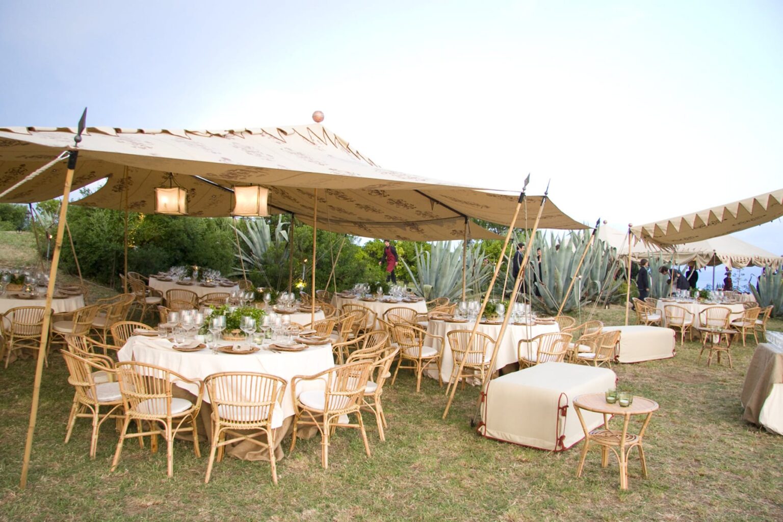Elegant outdoor dining setup featuring bamboo furniture and large tents, set in a lush garden environment for events or celebrations. | Only on SopranoVillas