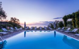 Serene outdoor swimming pool at sunset, surrounded by lounge chairs and lush greenery, creating a tranquil atmosphere for relaxation and leisure.