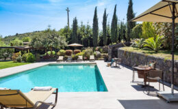 Luxurious outdoor pool area with sun loungers, umbrellas, and lush greenery in the background, perfect for relaxation and leisure.