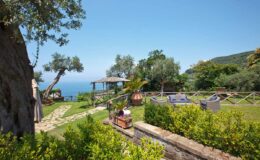 Scenic outdoor garden with lush greenery and ocean view, featuring a gazebo, lounge chairs, and a pathway, ideal for relaxation and nature enjoyment.