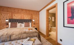 Cozy hotel room featuring a king-size bed with plush bedding, wooden paneling, modern decor, and an en-suite bathroom. Ideal for relaxation and comfort during your stay.