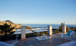 Scenic view from a modern terrace overlooking the ocean, featuring comfortable outdoor seating and vibrant decor, ideal for relaxation and enjoying sunsets.