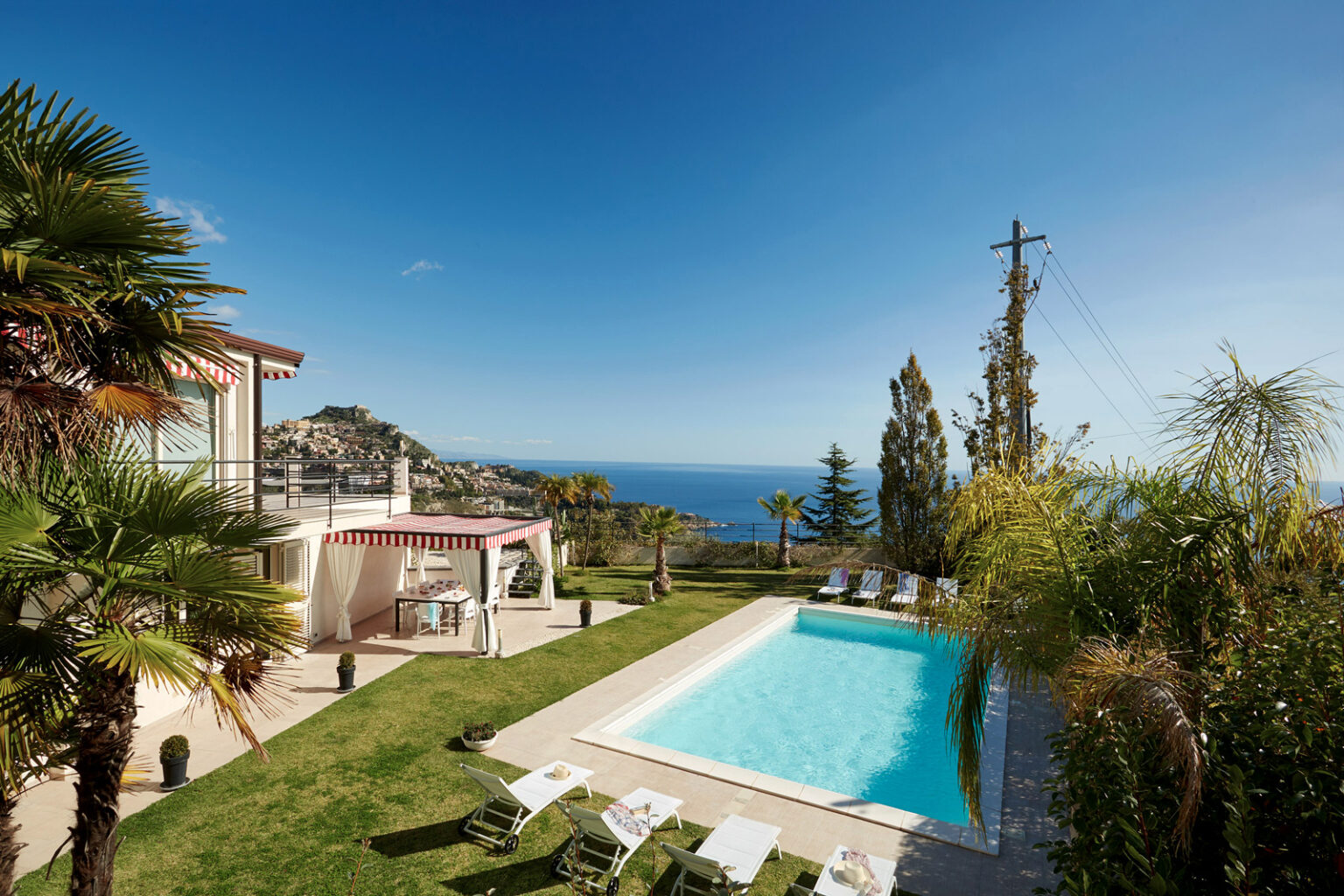 Luxurious villa with a swimming pool and ocean view, surrounded by lush greenery and palm trees, ideal for relaxation and outdoor living. | Only on SopranoVillas