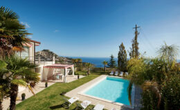 Luxurious villa with a swimming pool and ocean view, surrounded by lush greenery and palm trees, ideal for relaxation and outdoor living.