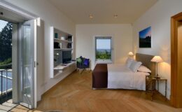 Modern bedroom with large windows offering scenic views, featuring a comfortable bed, sleek furniture, and stylish decor, perfect for relaxation and tranquility.