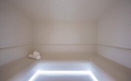 Minimalist spa treatment room featuring soft white towels and ambient lighting, designed for relaxation and wellness.