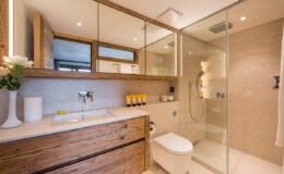 Modern bathroom interior featuring a sleek glass shower, wooden cabinetry, and elegant lighting, creating a stylish and functional space.