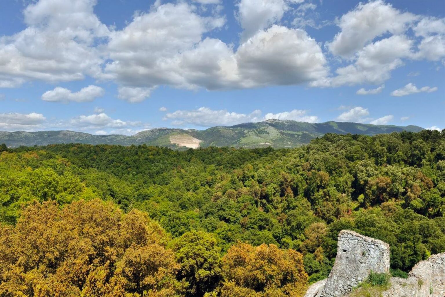 Scenic view of lush green hills and forests under a partly cloudy sky, highlighting the natural beauty of the landscape. | Only on SopranoVillas