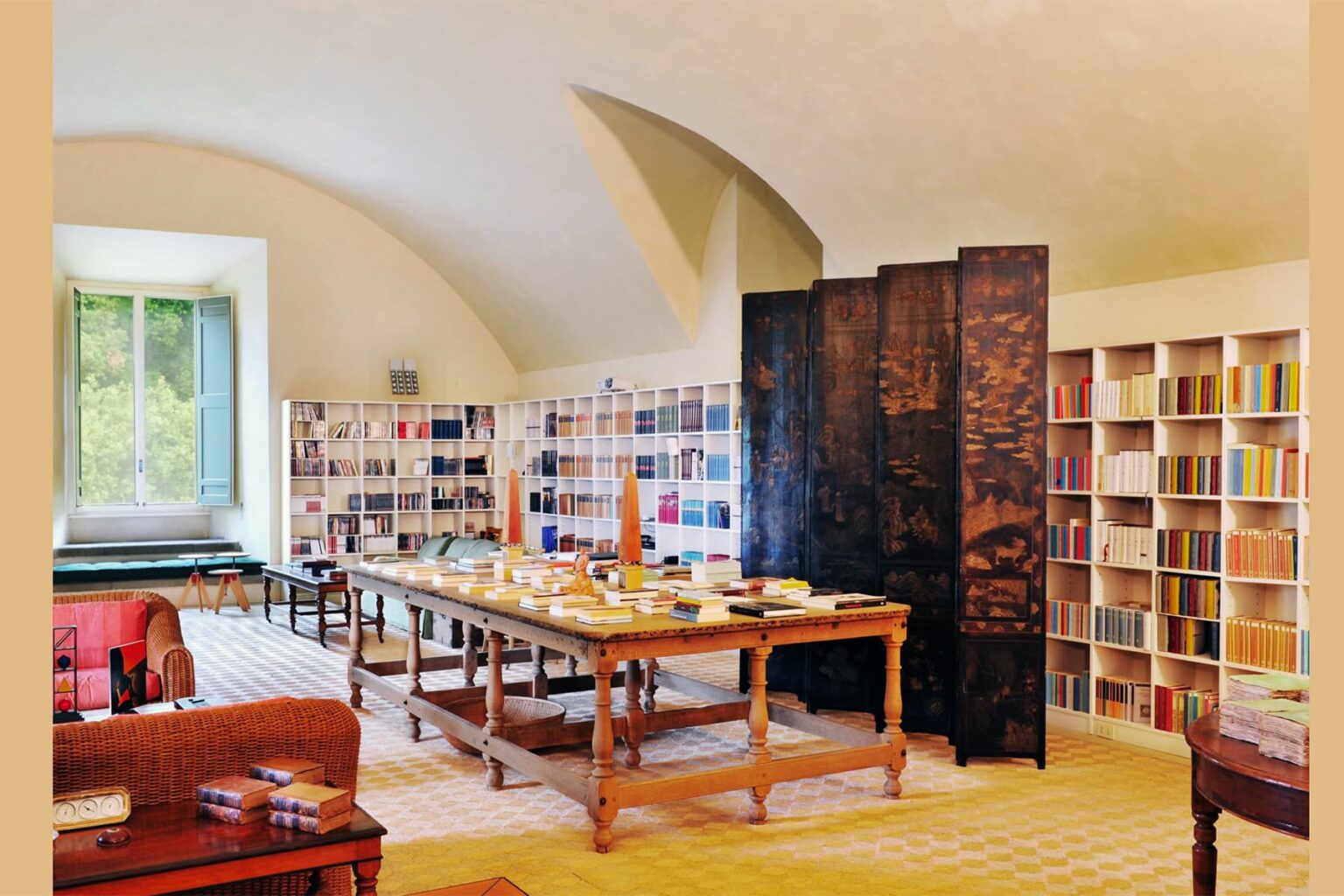 Interior view of a cozy library featuring wooden tables, bookshelves filled with colorful books, and large windows allowing natural light. The space has an inviting atmosphere, perfect for reading and studying. | Only on SopranoVillas