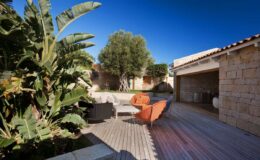 Outdoor patio area featuring modern furniture, lush greenery, and a clear blue sky, ideal for relaxation and entertaining.