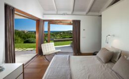 Modern bedroom with large glass doors opening to a scenic outdoor view, featuring a minimalistic design, neutral color palette, and stylish furnishings.