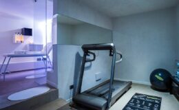 Modern home gym featuring a treadmill, exercise mat, and stability ball in a stylish, minimalist setting with ambient lighting.