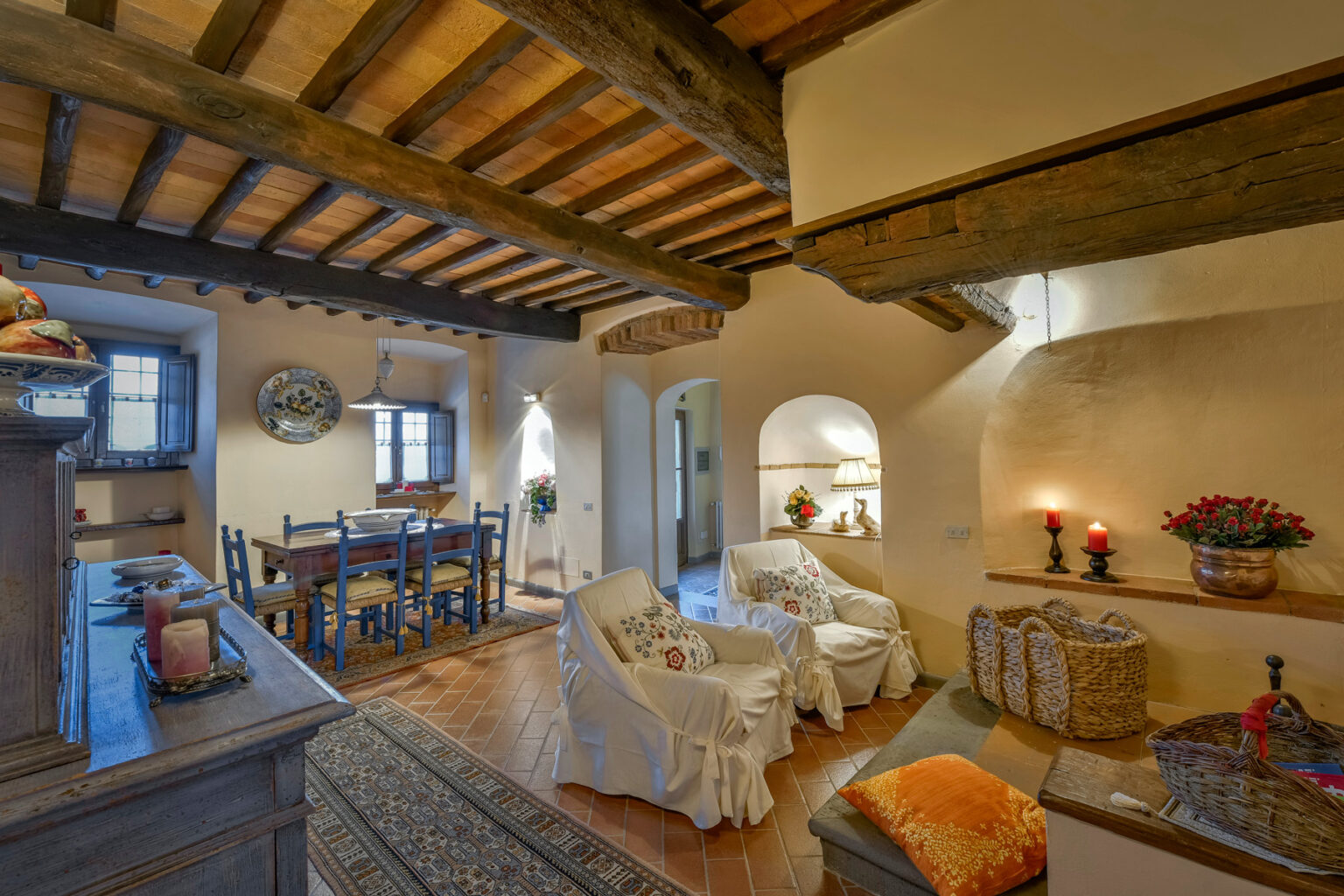 Cozy living room with rustic wooden beams, featuring a comfortable seating area, dining table, and warm decorative elements, creating an inviting atmosphere. | Only on SopranoVillas