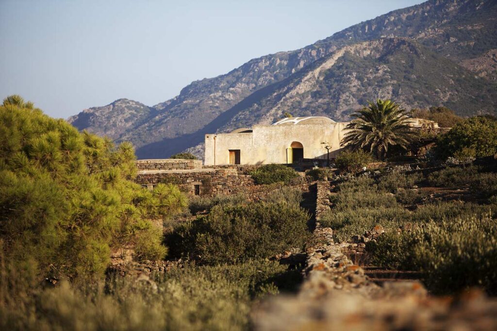 Historic building surrounded by lush greenery and mountains, showcasing a serene landscape in a Mediterranean setting. | Only on SopranoVillas