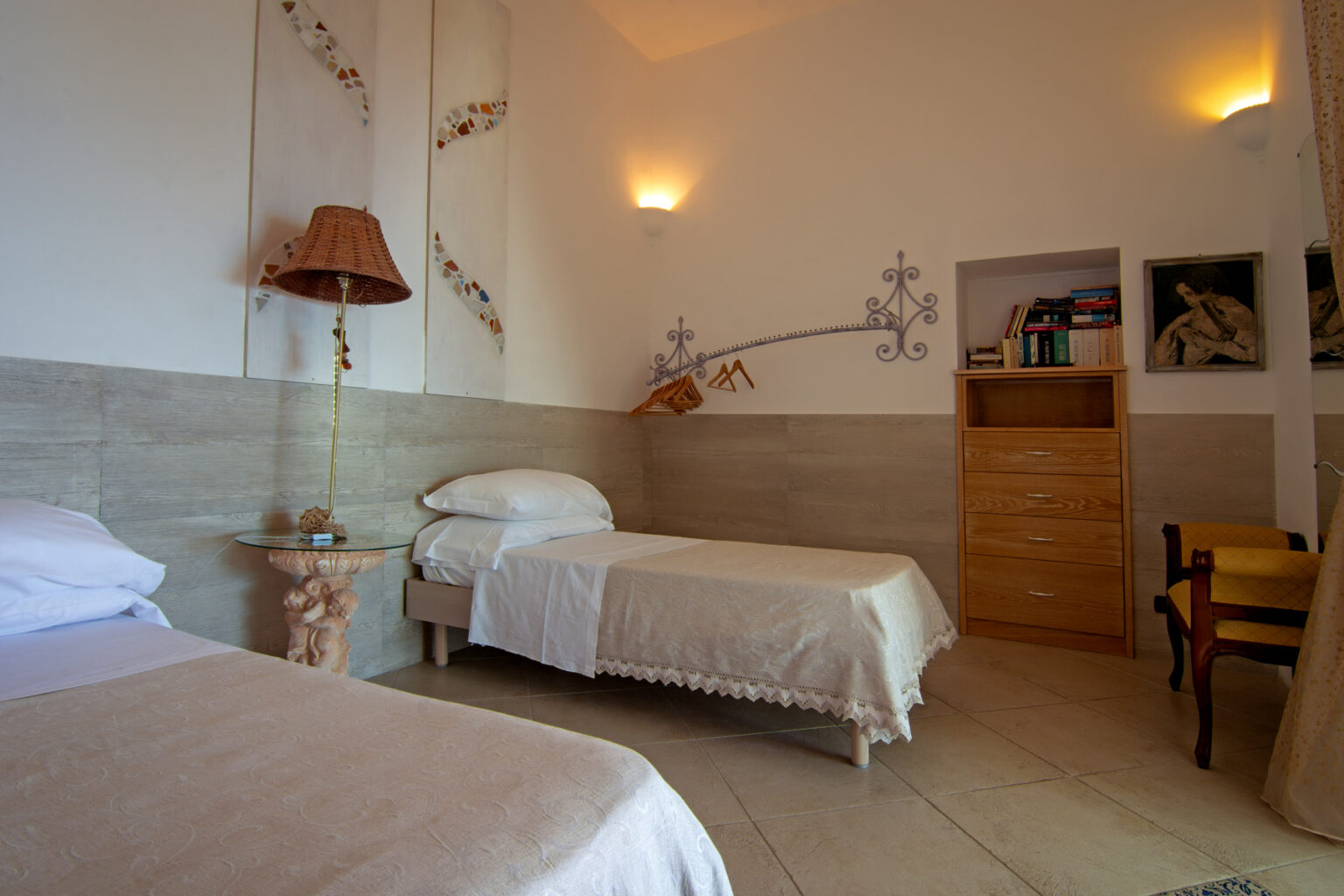 Cozy guest room with two single beds, elegant decor, and soft lighting, featuring a wooden dresser and wall art, ideal for a relaxing stay. | Only on SopranoVillas