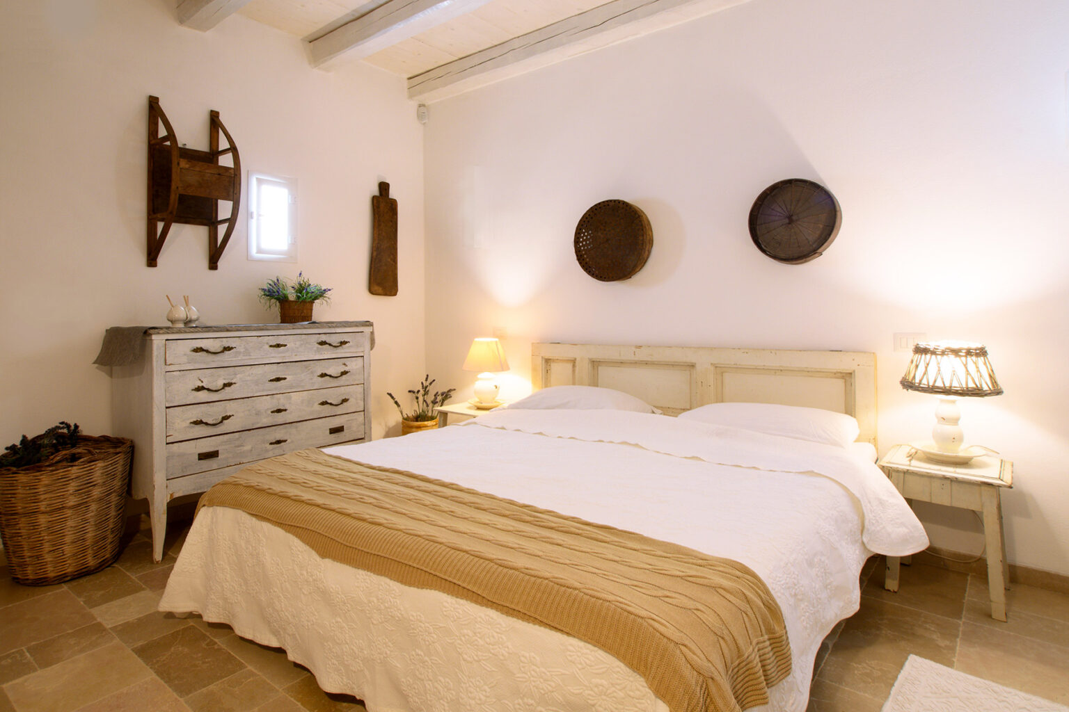 Cozy bedroom featuring a double bed with a beige and white color scheme, wooden dresser, decorative wall plates, and soft lighting, creating a warm and inviting atmosphere. | Only on SopranoVillas