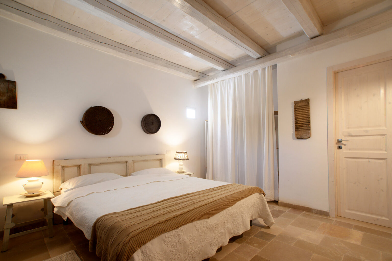 Cozy bedroom with a double bed, wooden beams, soft lighting, and decorative wall art, featuring neutral tones and a warm ambiance. | Only on SopranoVillas