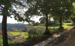 Scenic landscape view featuring lush greenery, trees, and terraced gardens overlooking a valley under clear skies. Ideal for nature lovers and outdoor enthusiasts.