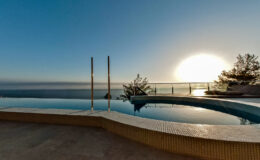 Infinity pool overlooking the ocean at sunset, featuring a serene atmosphere and modern design elements.