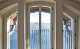 Elegant arched windows with a view of mountains and a serene lake, showcasing a modern architectural design and natural light.