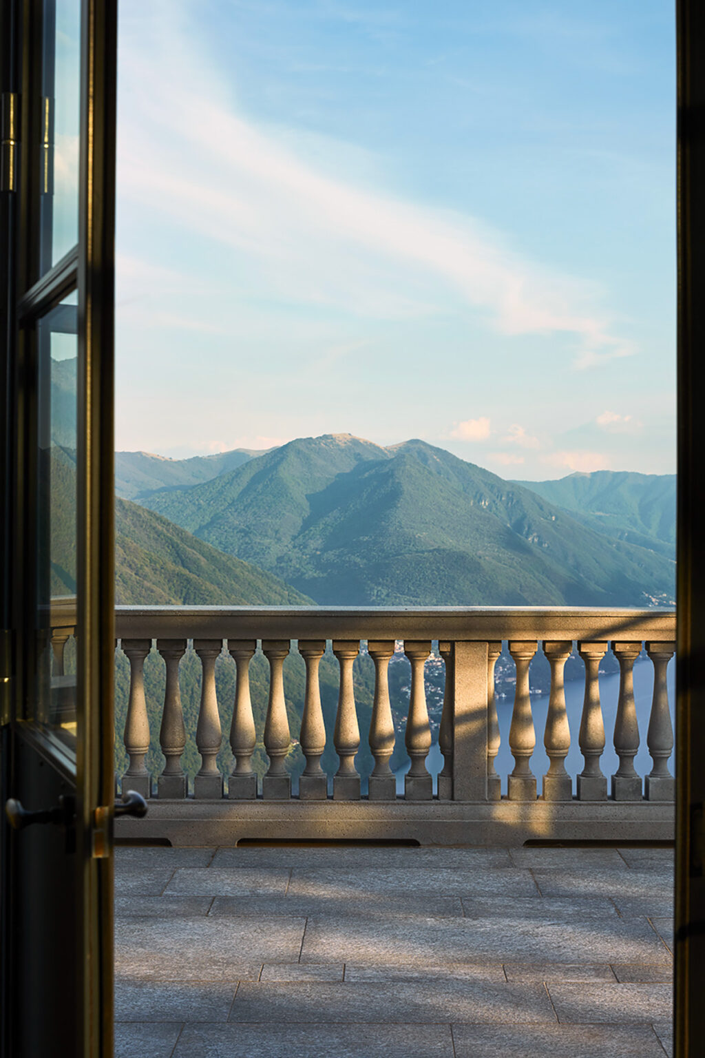Scenic mountain view from a balcony with a decorative railing, showcasing lush green hills under a clear sky. | Only on SopranoVillas